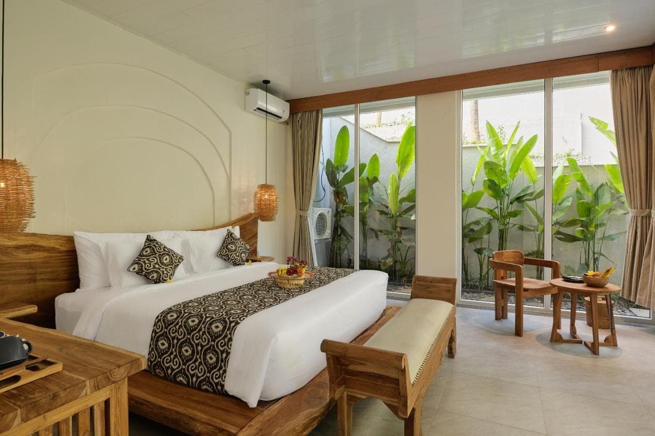 a hotel room with a bed and a window at Changi Jungle Ubud Villas in Ubud