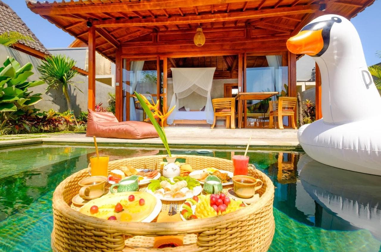 a swimming pool with a tray of food next to a swan at Canggu Wooden Green Paradise in Canggu