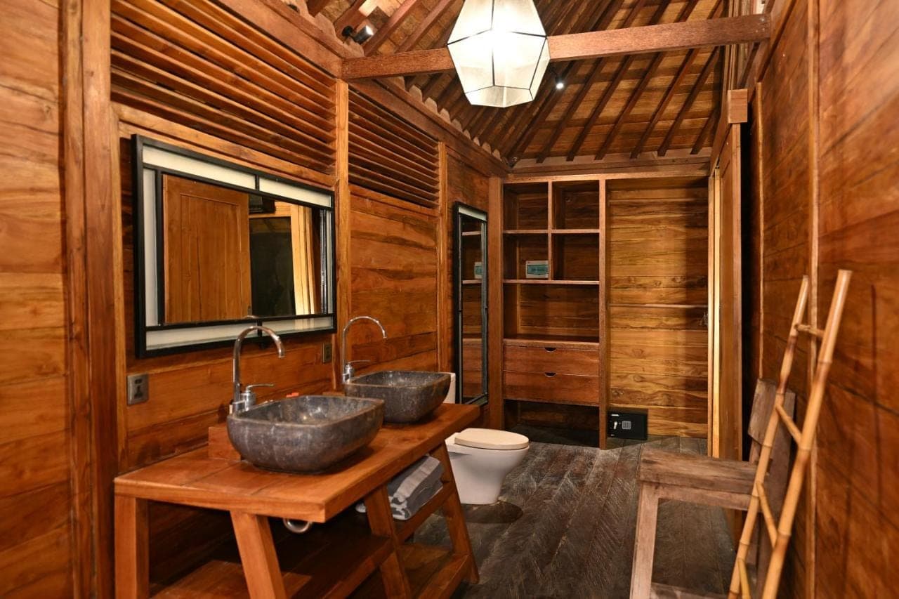 two sinks in a wooden bathroom with a toilet at Canggu Wooden Green Paradise in Canggu