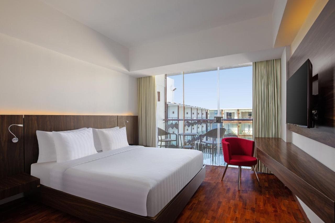 a hotel room with a bed and a balcony at The Bene Hotel in Kuta