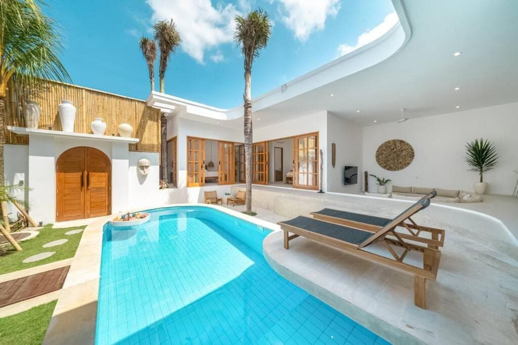 a swimming pool in a villa with palm trees at Villa TOLOSA - Modern 3BR - Central Canggu Beach in Canggu