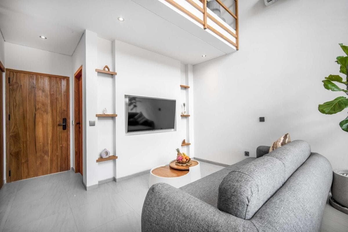 a living room with a couch and a tv at Pererenan Gate Brand New 1BR Retreat In Canggu in Canggu