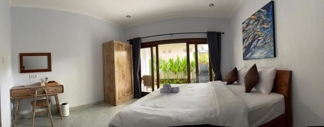 a bedroom with a large bed and a table at Holiday Guest House in Amed