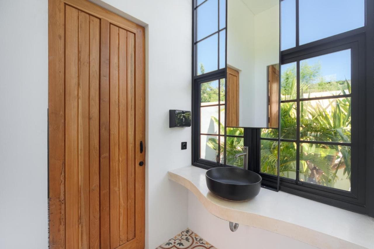 a bathroom with a black bowl on a shelf next to a window at The Lazy Lama Hostel Uluwatu in Uluwatu