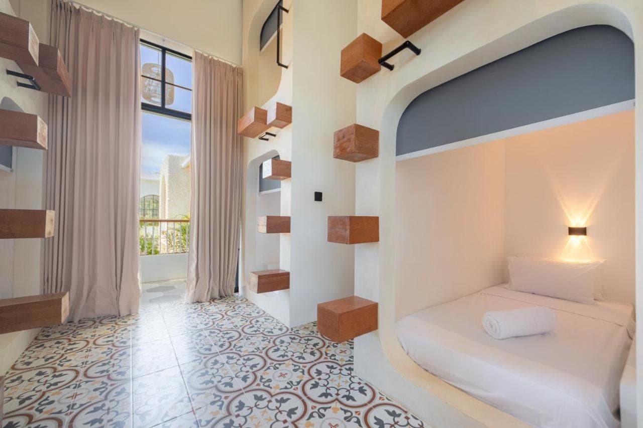 a bedroom with a bed and a window at The Lazy Lama Hostel Uluwatu in Uluwatu
