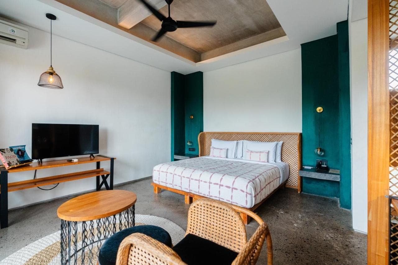 a bedroom with a bed and a desk and a tv at Shore Amora Canggu in Canggu