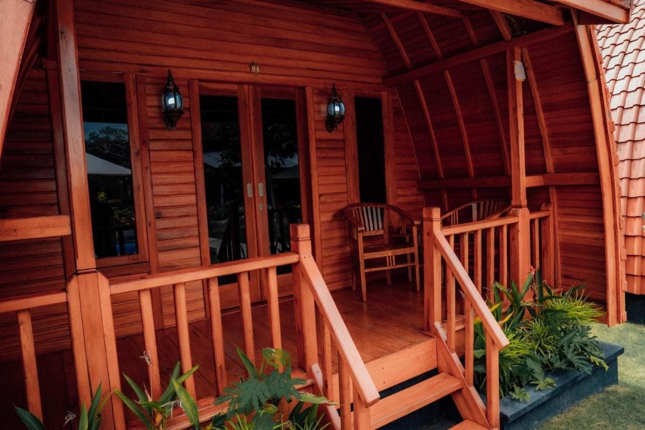 a porch of a wooden cabin with two chairs at Nusa Dua Huts Pondok Gajah Para by EPS in Nusa Dua