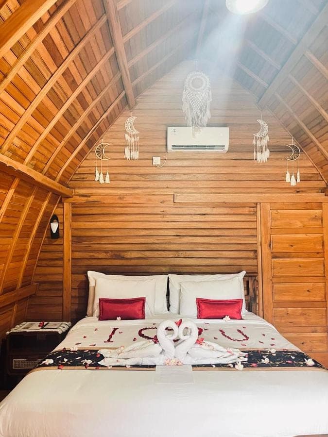 a bedroom with a bed with two swans on it at Nusa Dua Huts Pondok Gajah Para by EPS in Nusa Dua