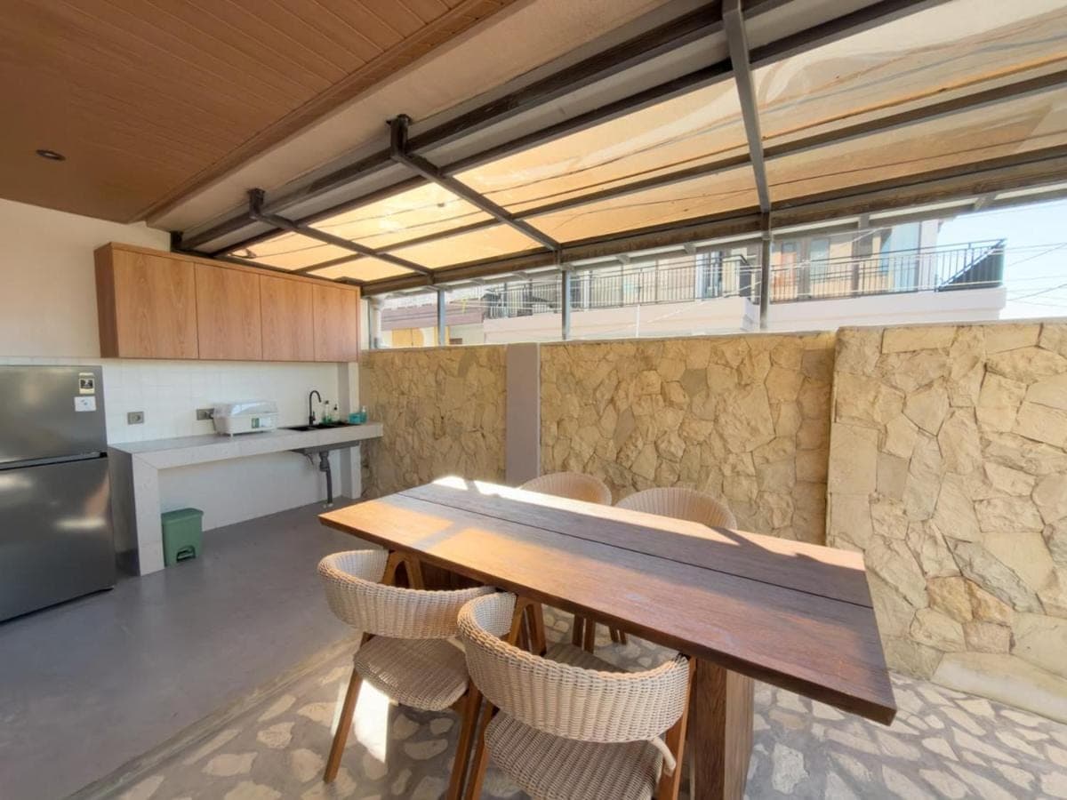 a kitchen with a wooden table and chairs at Mattea Guest House Nusa Dua Bali in Nusa Dua
