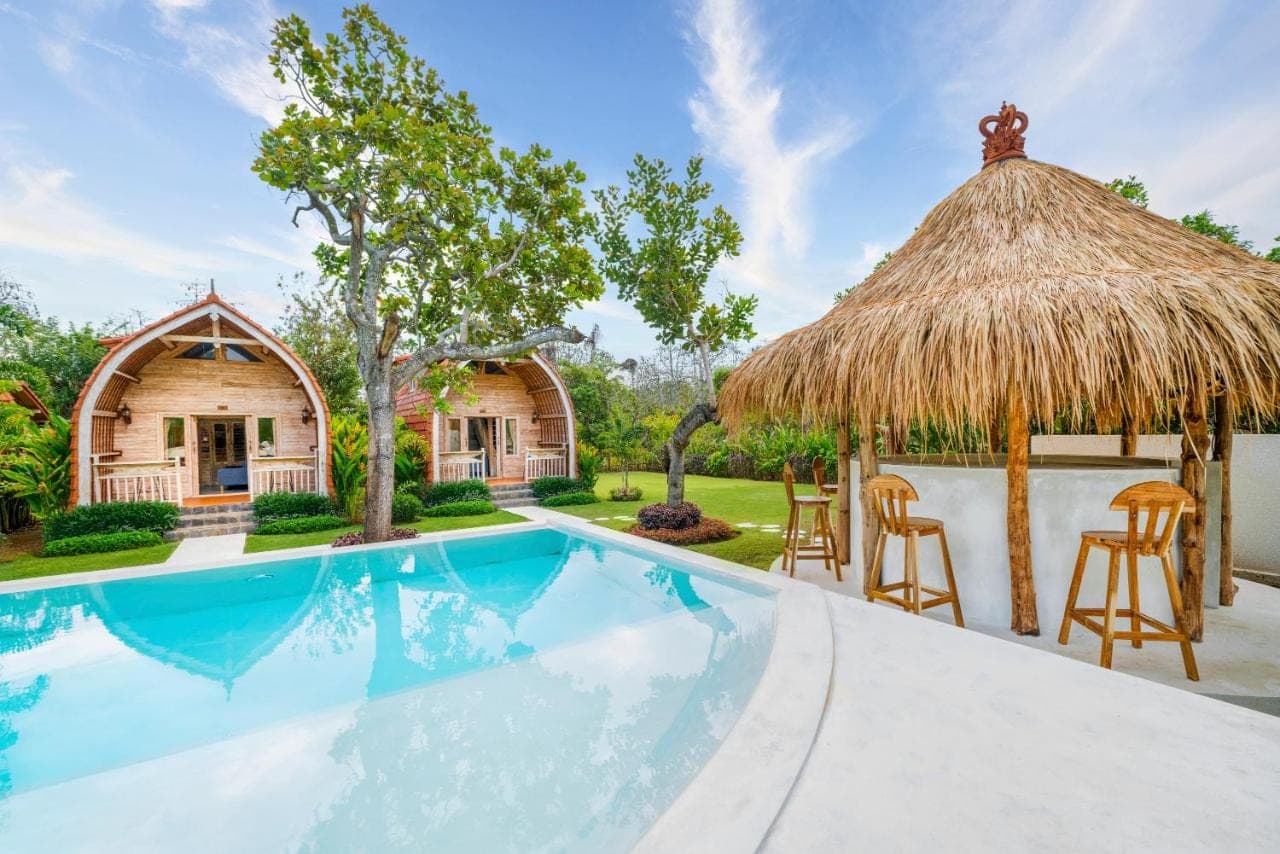 a home with a swimming pool and a thatch roof at Uluwatu Desa in Uluwatu