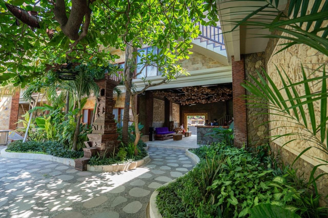 a building with a courtyard with trees and plants at Amed Paradise Beach Club in Amed