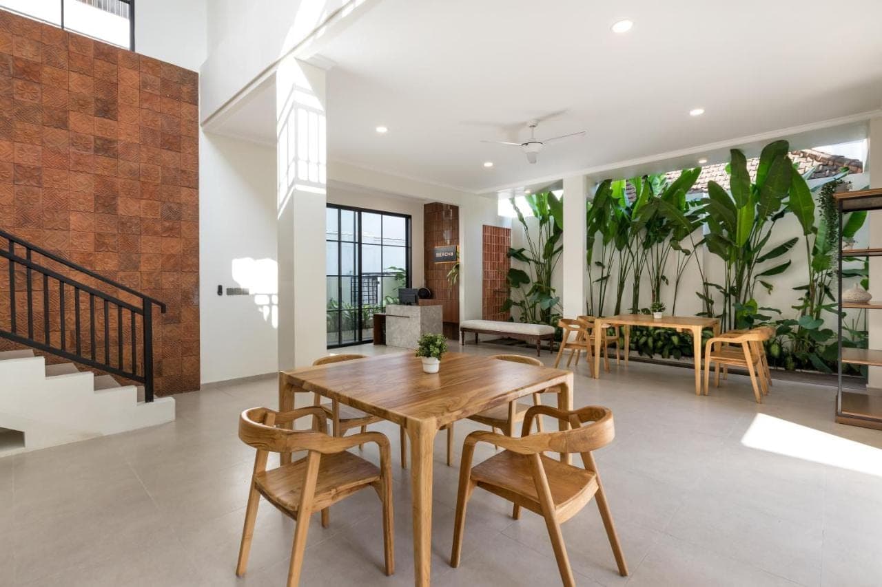 a dining room with a wooden table and chairs at Beach8 Canggu by Kerta Living in Canggu