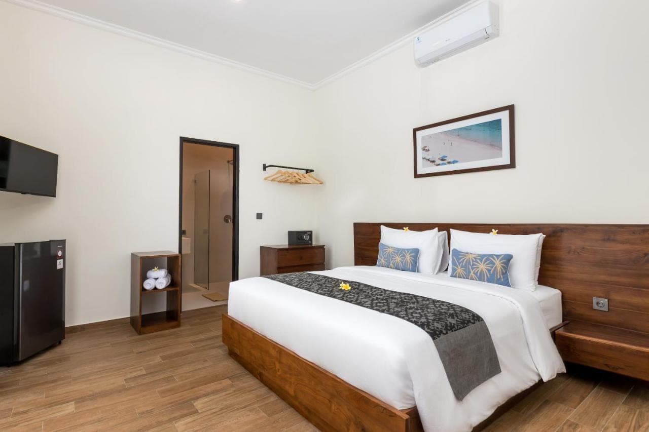 a bedroom with a large bed and a flat screen tv at Beach8 Canggu by Kerta Living in Canggu