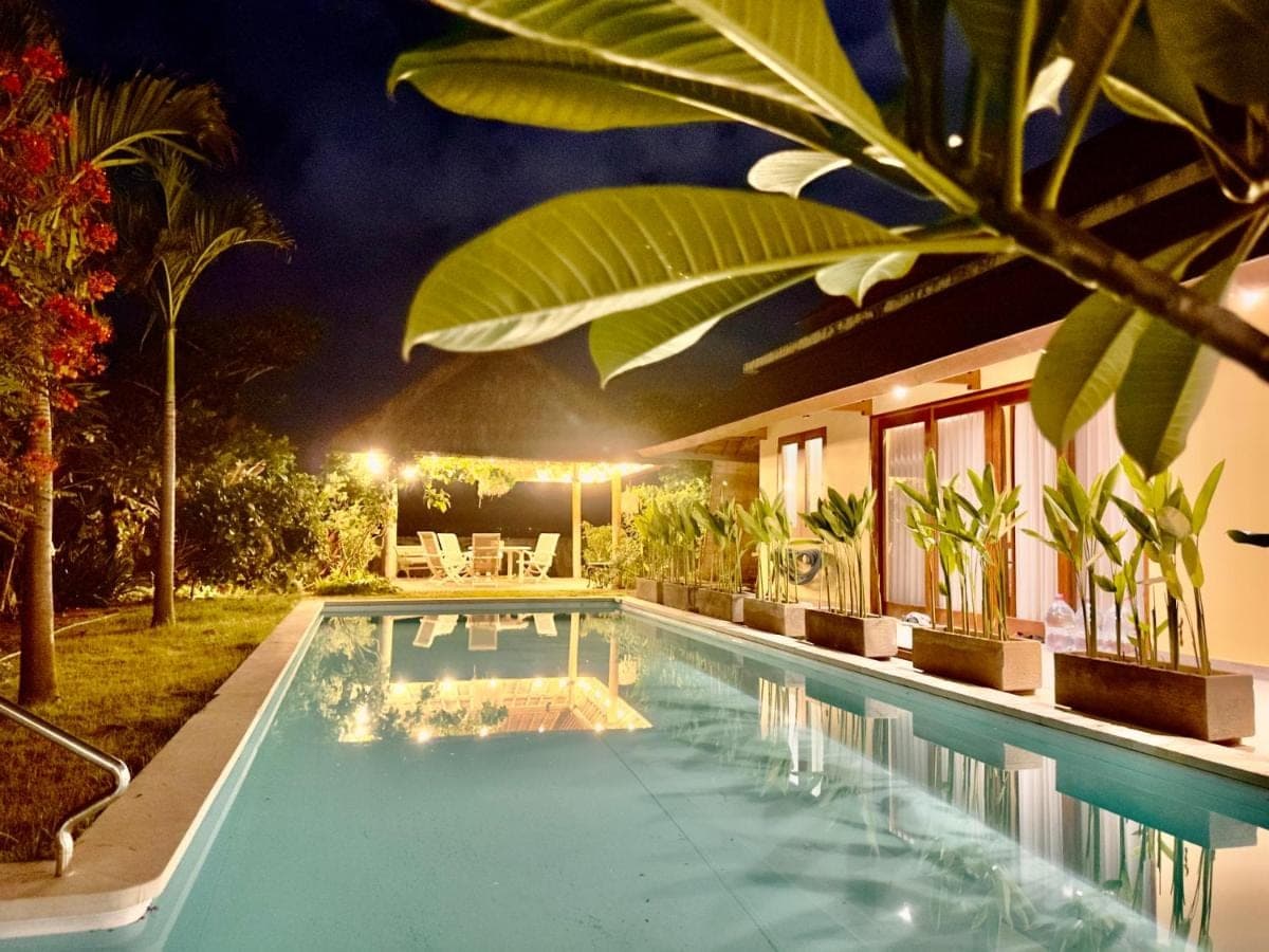 a swimming pool in front of a house at night at Sanur ocean view villas in Sanur