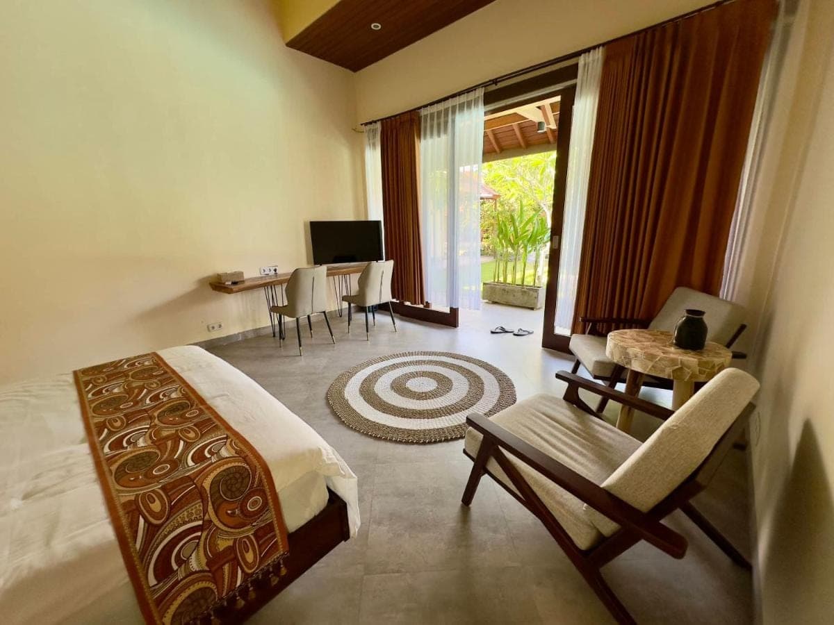 a bedroom with a bed and a living room with a desk at Sanur ocean view villas in Sanur