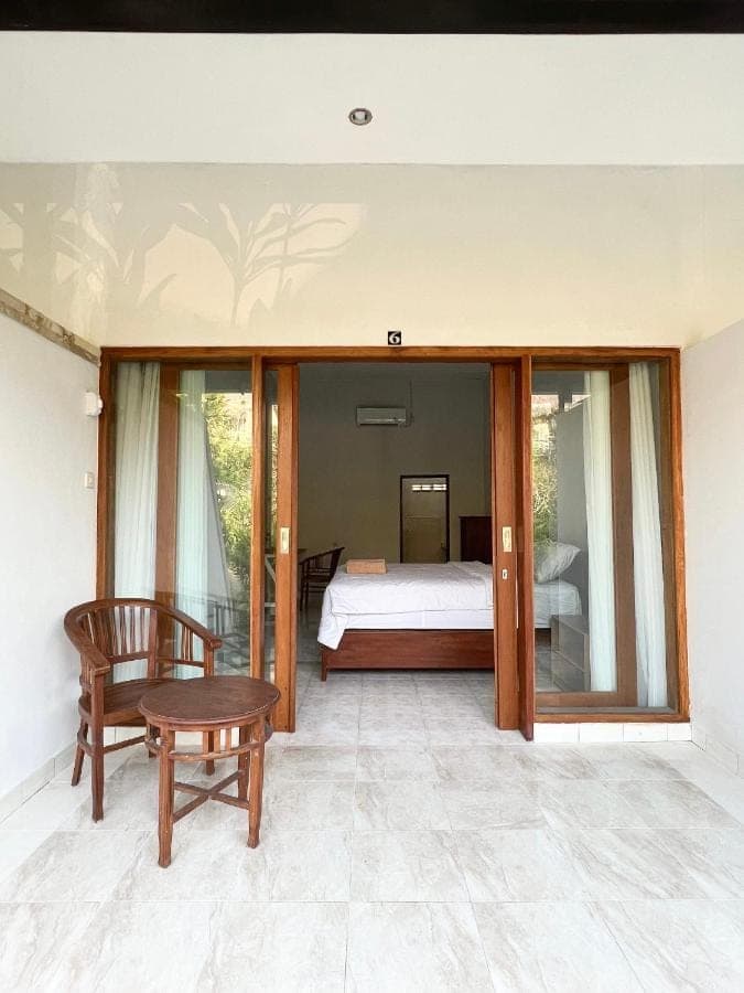 a bedroom with a bed and a chair at D'pandawa guest house in Nusa Dua