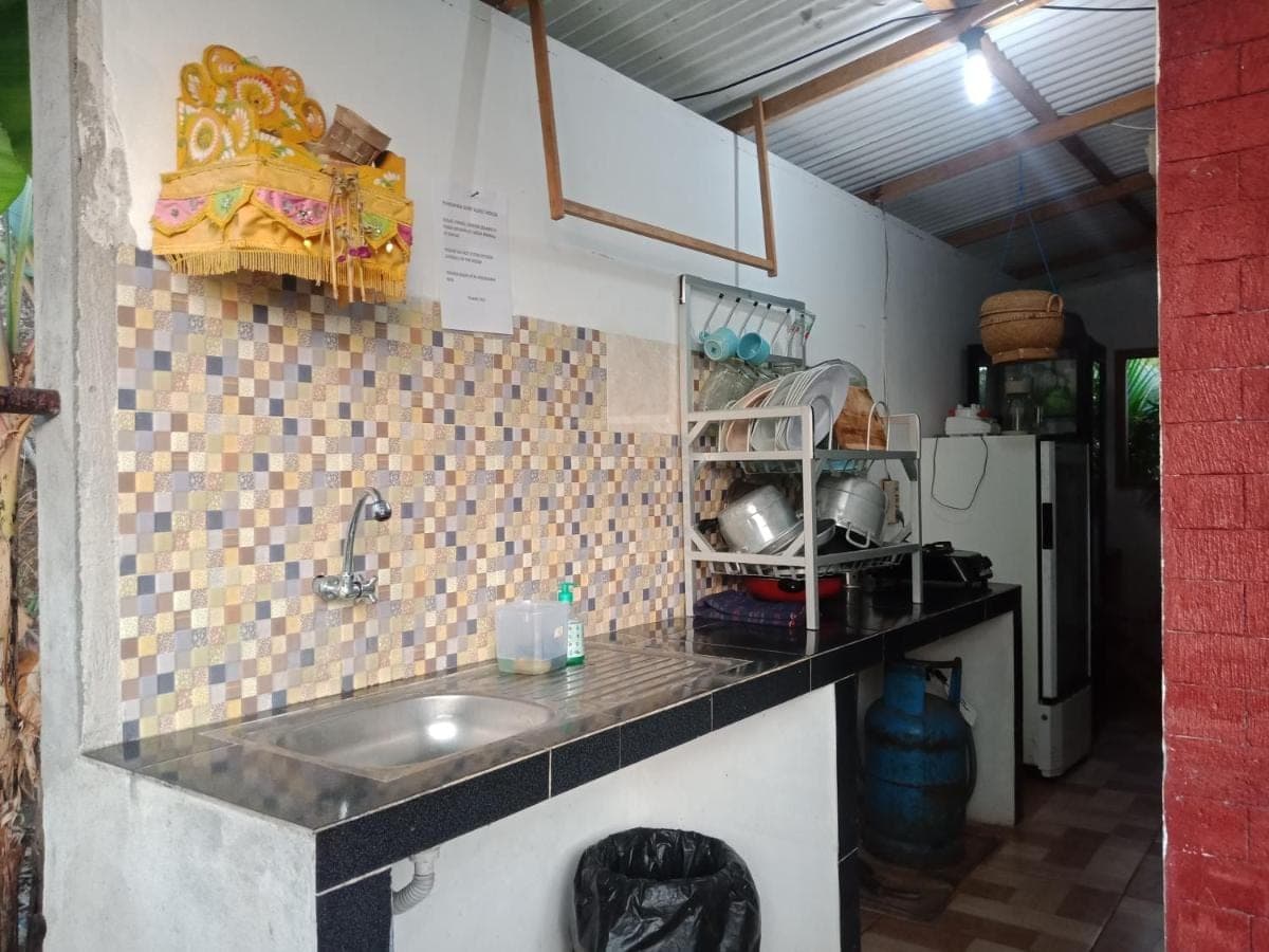 a kitchen counter with a sink and a refrigerator at D'pandawa guest house in Nusa Dua