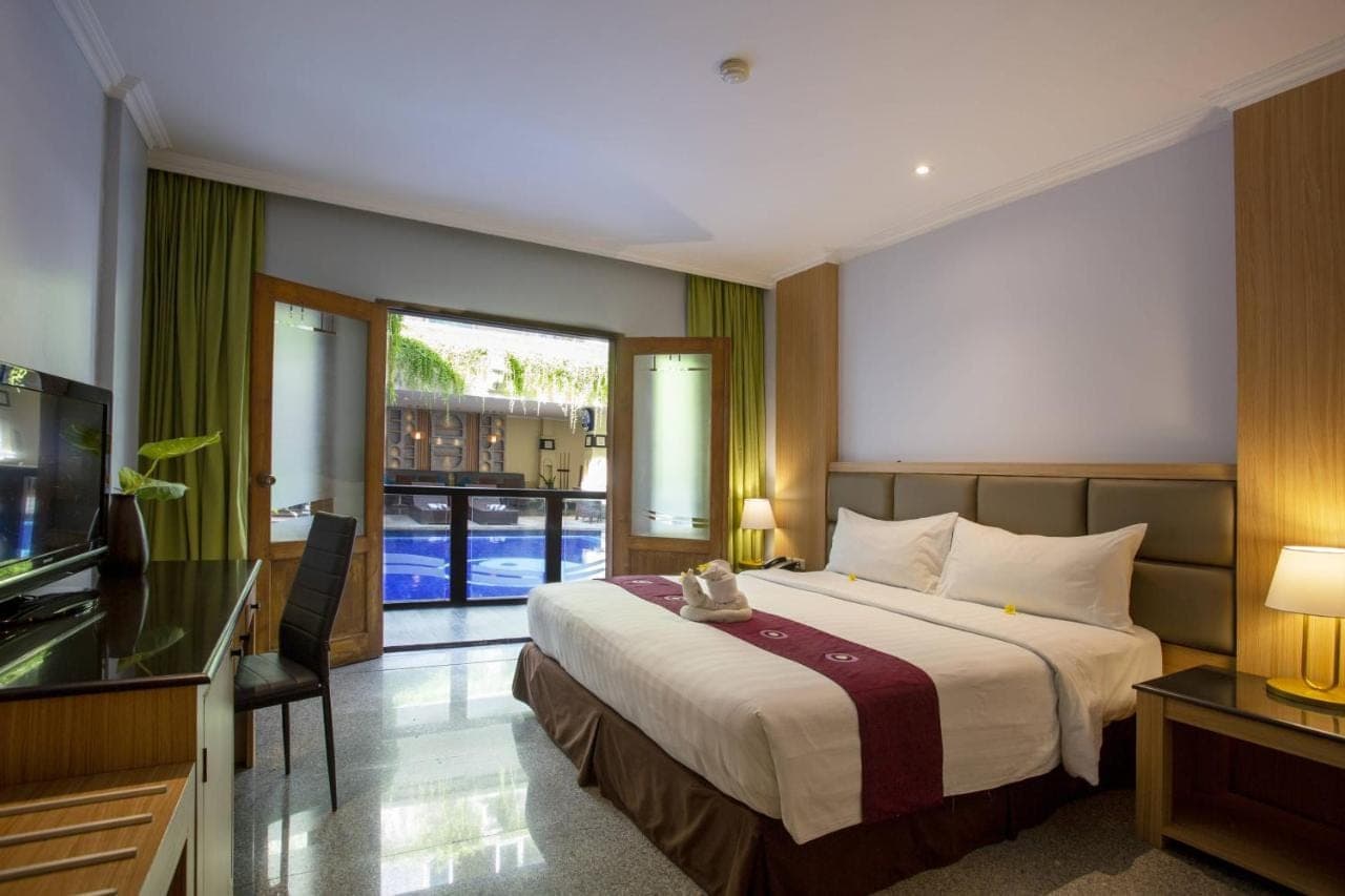 a hotel room with a bed and a television at Famous Hotel Kuta Formerly Permata Kuta Hotel in Kuta