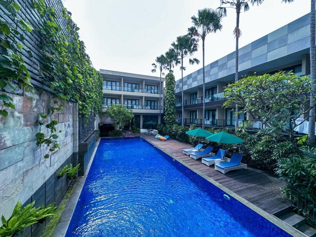 a swimming pool with chairs and umbrellas next to a building at Dekuta in Kuta