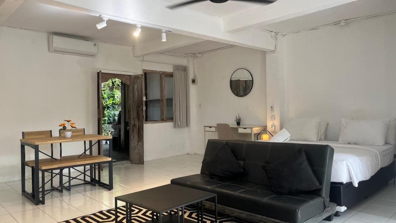 a bedroom with a bed and a couch and a table at Kampoeng Saya in Seminyak