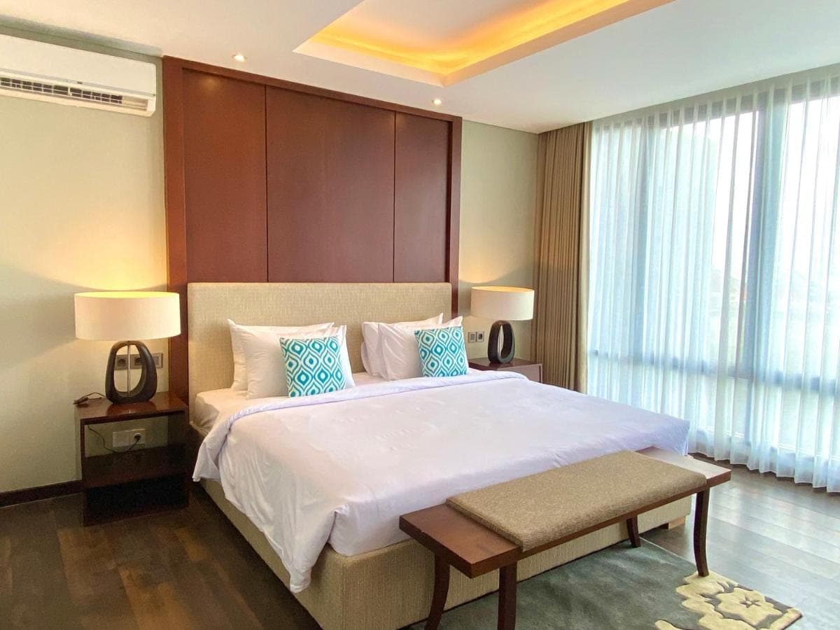 a bedroom with a large white bed with blue pillows at Bloomingville Villas in Nusa Dua in Nusa Dua