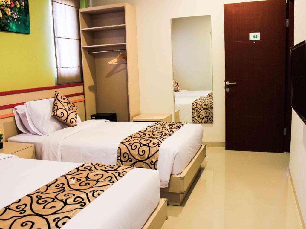 a hotel room with two beds and a mirror at Kemuning Kuta Hotel in Kuta