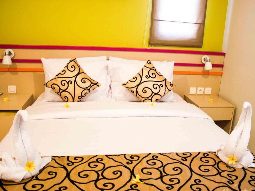 a bedroom with a bed with white sheets and pillows at Kemuning Kuta Hotel in Kuta