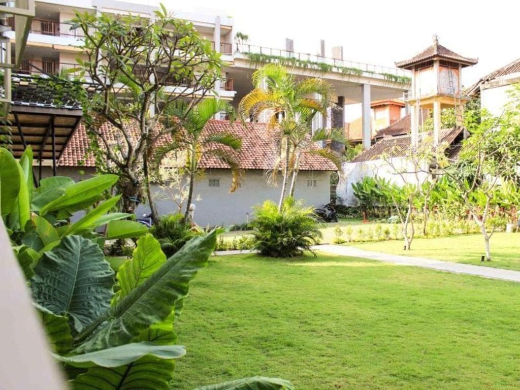 a garden with a building in the background at Kemuning Kuta Hotel in Kuta