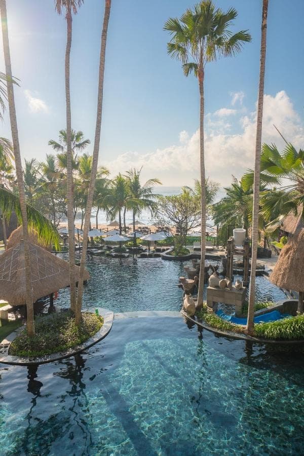 a pool at the resort with palm trees at Holiday Inn Resort Bali Nusa Dua by IHG in Nusa Dua