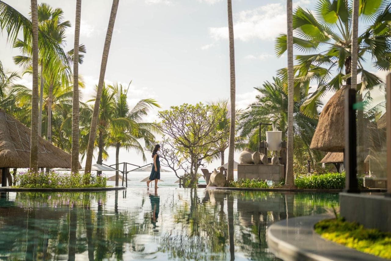 a woman walking through a pool at a resort at Holiday Inn Resort Bali Nusa Dua by IHG in Nusa Dua