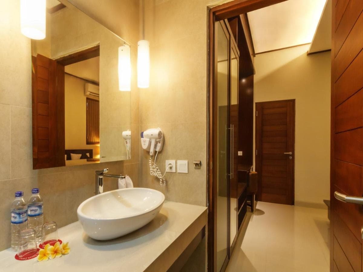 a bathroom with a sink and a phone on a counter at Yulia Beach Inn Kuta in Kuta