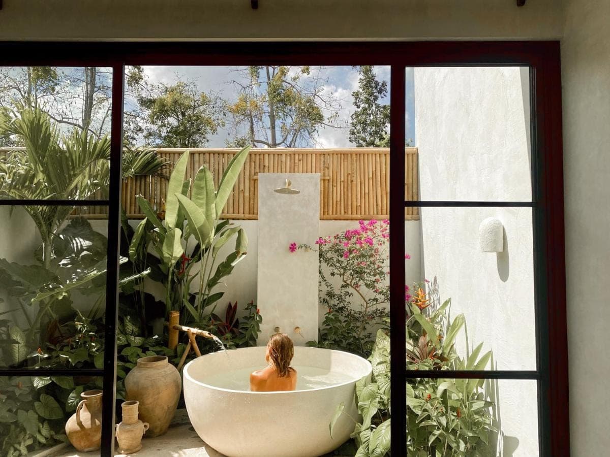 a woman sitting in a bath tub in a garden at Alma Bingin Boutique Hotel in Uluwatu