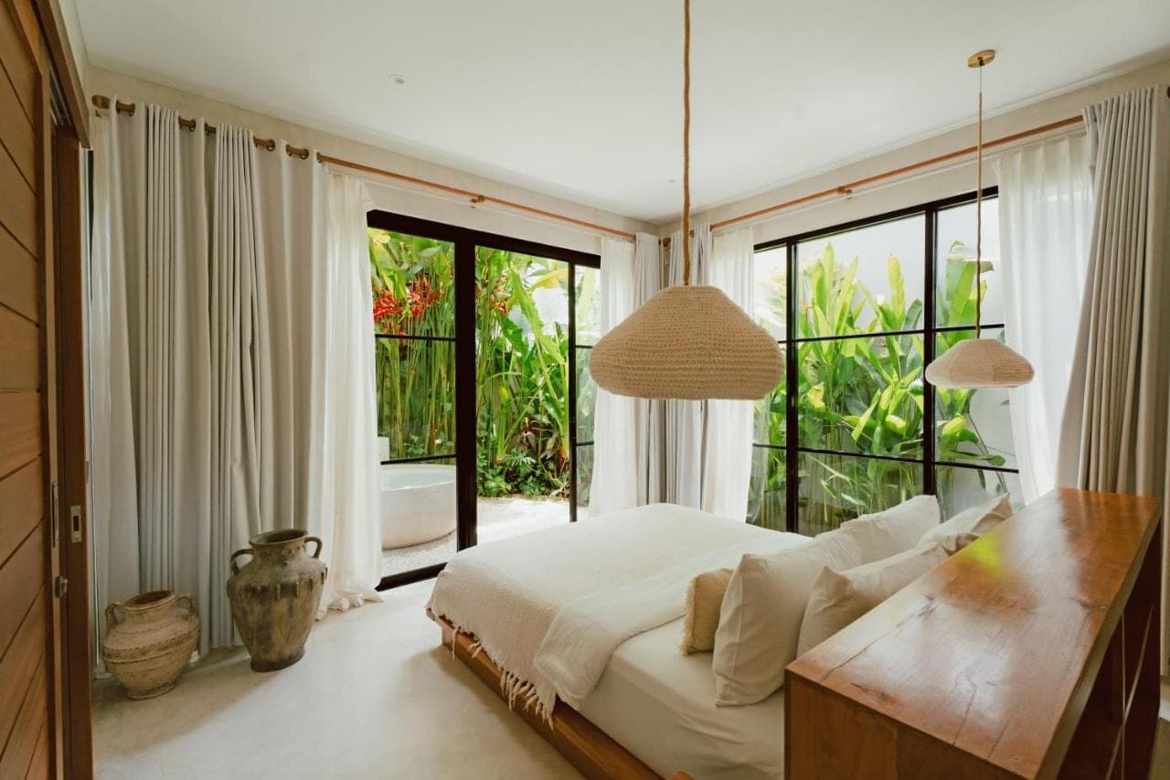 a bedroom with a large bed and large windows at Alma Bingin Boutique Hotel in Uluwatu