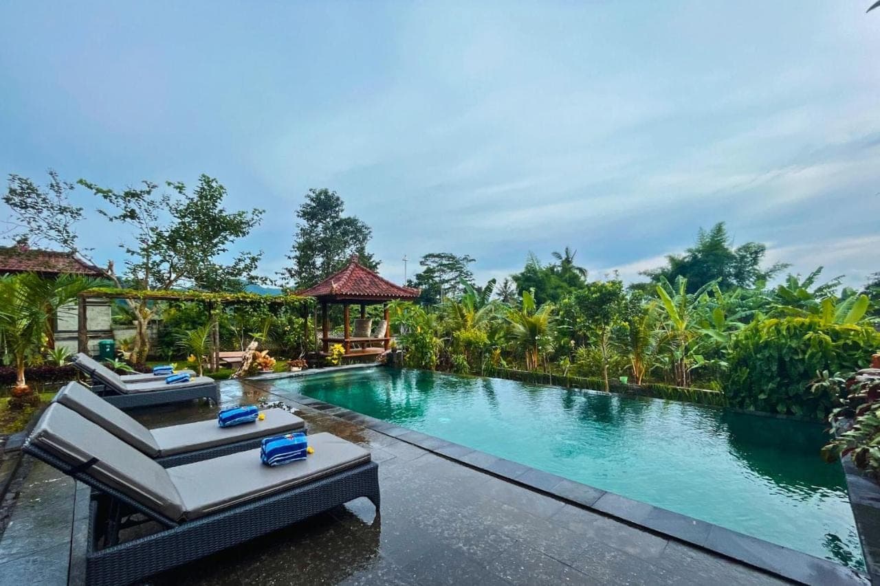 a swimming pool with lounge chairs in a resort at Villa Pastiny Santy Sidemen in Sidemen