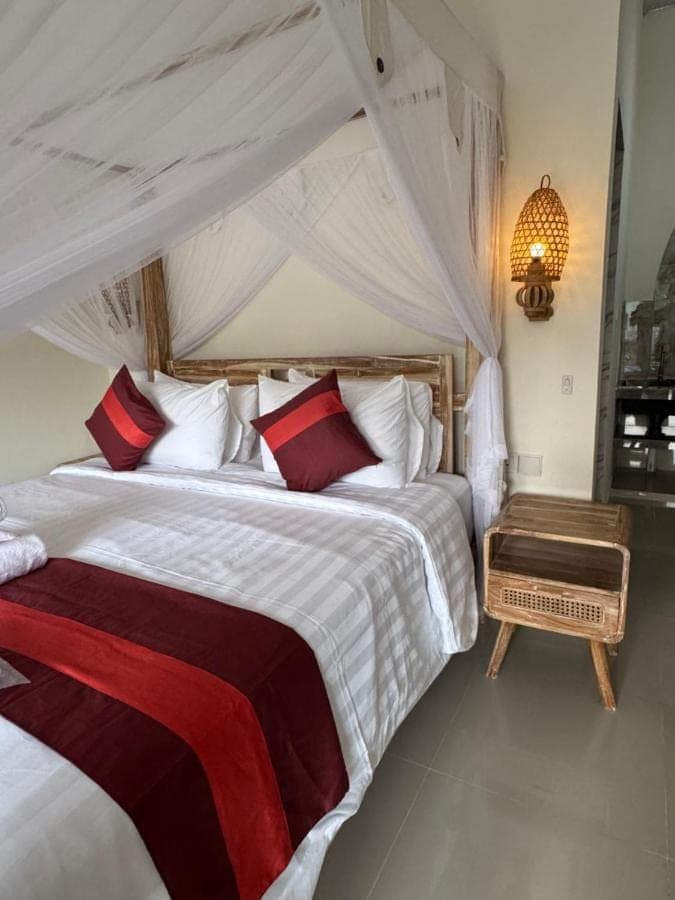 a bedroom with a large bed with red and white pillows at Comeon Amed in Amed