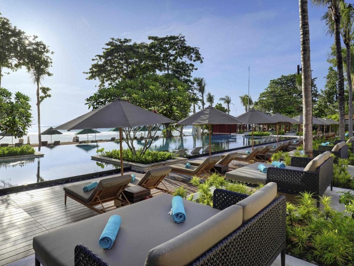 a resort with a pool and tables and chairs at Novotel Bali Benoa in Nusa Dua