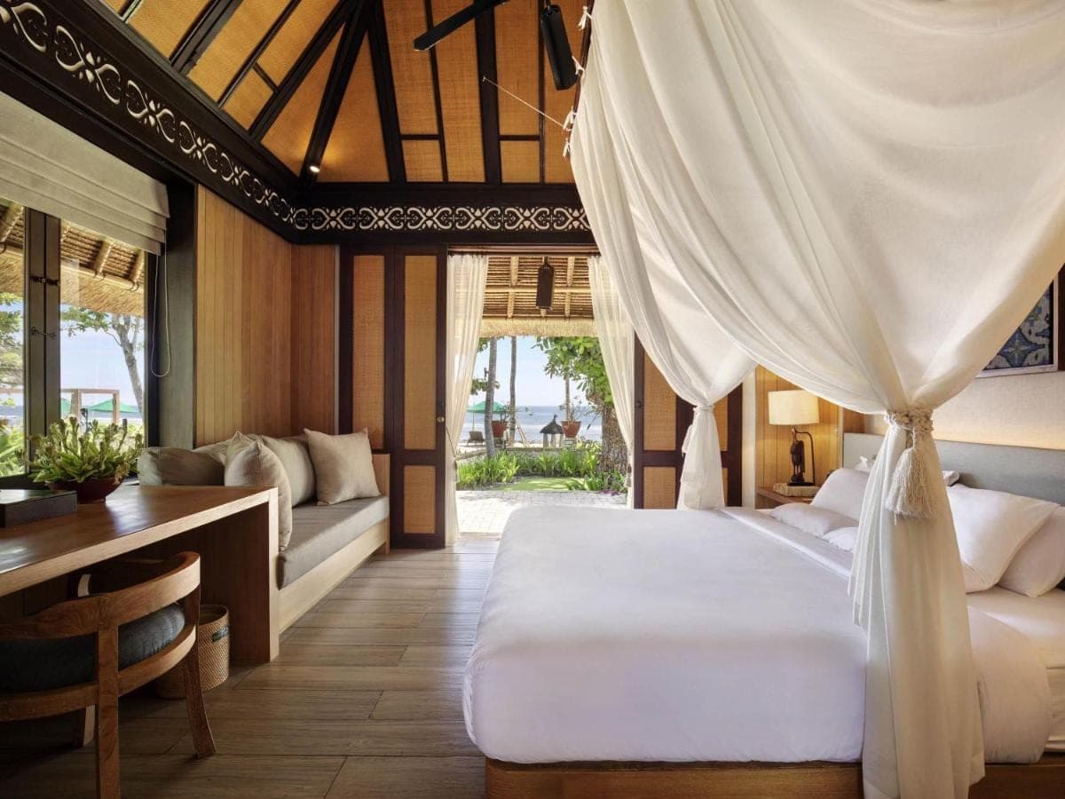 a bedroom with a bed and a desk and a table at Novotel Bali Benoa in Nusa Dua