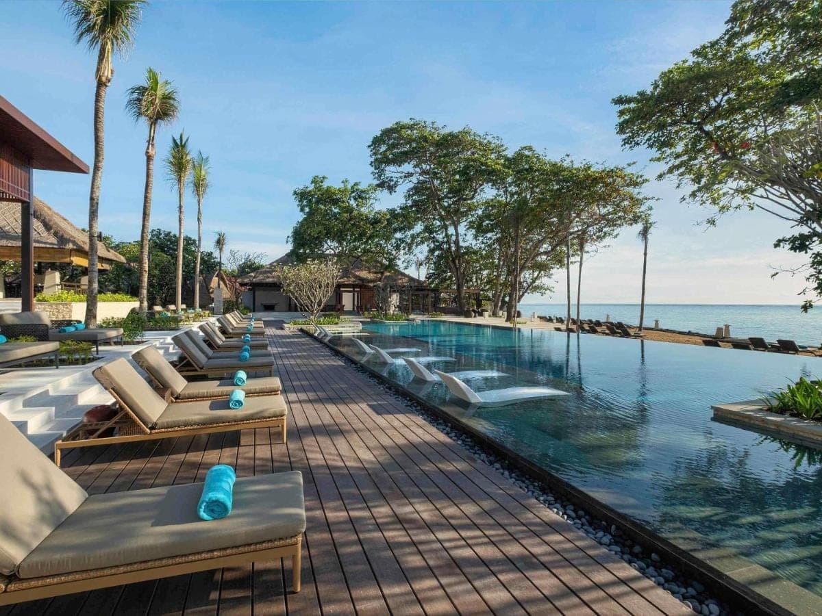 a row of lounge chairs next to a swimming pool at Novotel Bali Benoa in Nusa Dua
