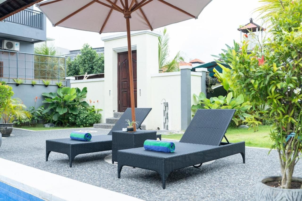two chairs and an umbrella next to a pool at The Kifaraju Nusa Dua Bali in Nusa Dua