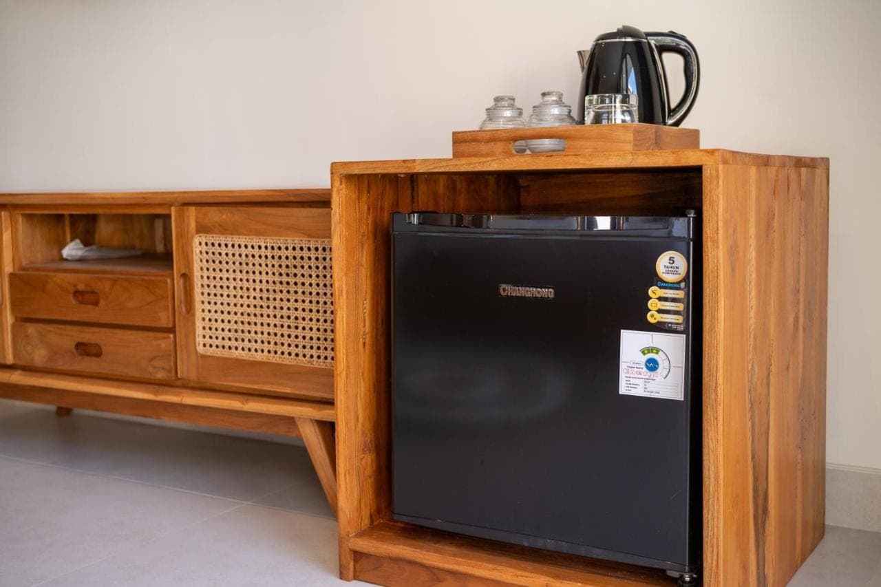 a black refrigerator sitting next to a wooden cabinet at Uluwatu Bagus Homestay in Uluwatu