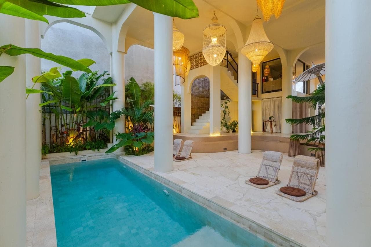 a pool in a house with chairs and a porch at Djati Retreat & Yoga Lounge by Pertama Stay in Nusa Dua