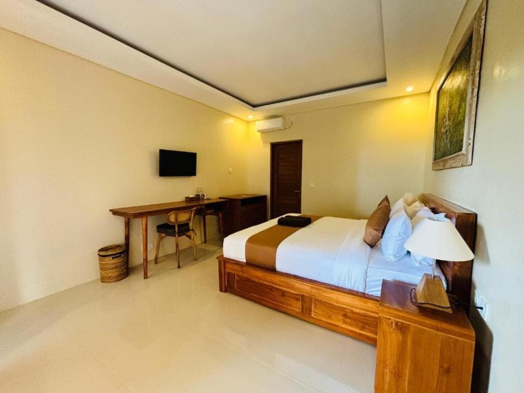 a bedroom with a bed and a desk in a room at Pondok Wisata Amerta Semaya Agung in Ubud