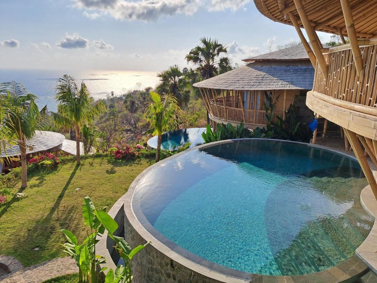 an infinity pool at a resort with the ocean in the background at Villas Bukit Lipah in Amed