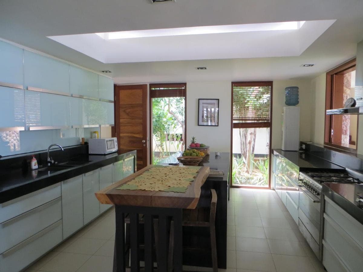 a kitchen with white cabinets and a wooden counter top at Villa Bukit Segara in Amed
