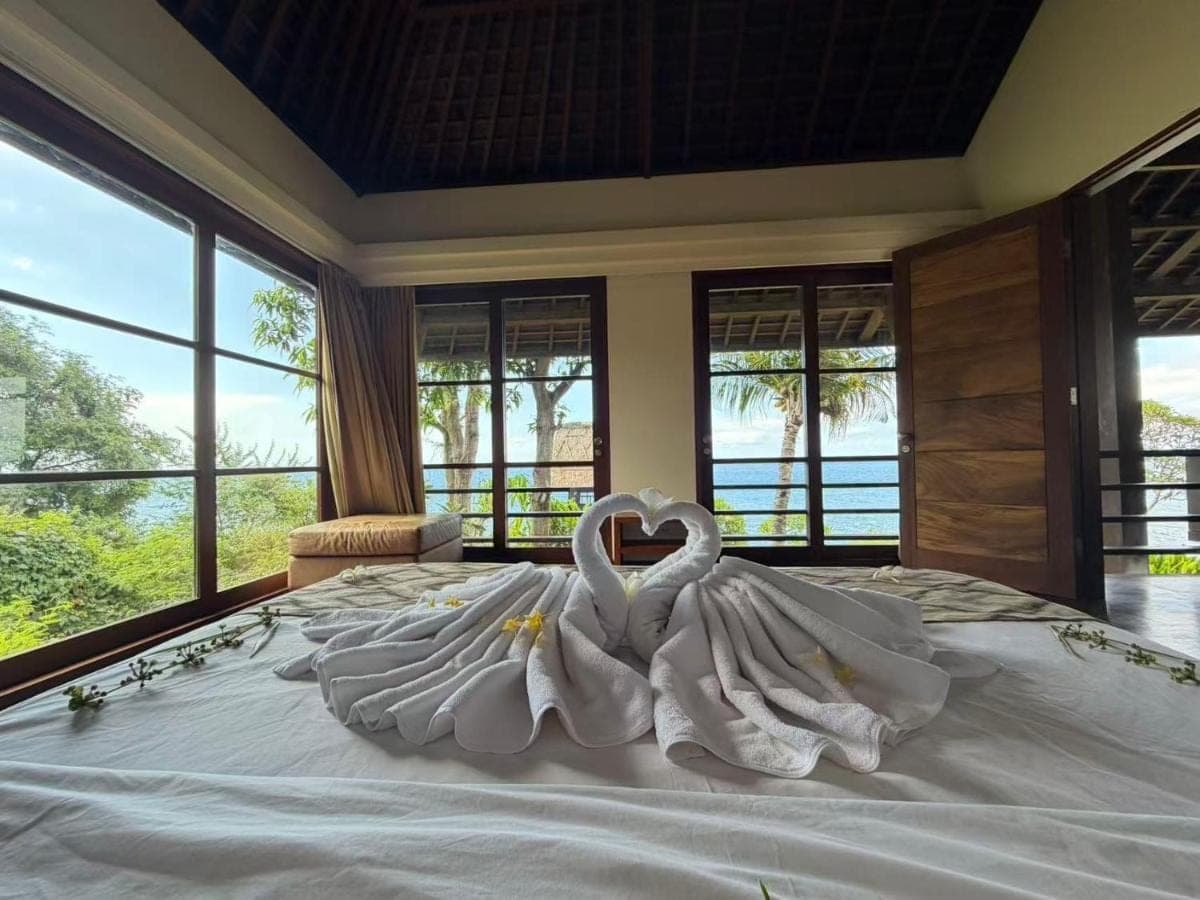 two white swans sitting on top of a bed at Villa Bukit Segara in Amed