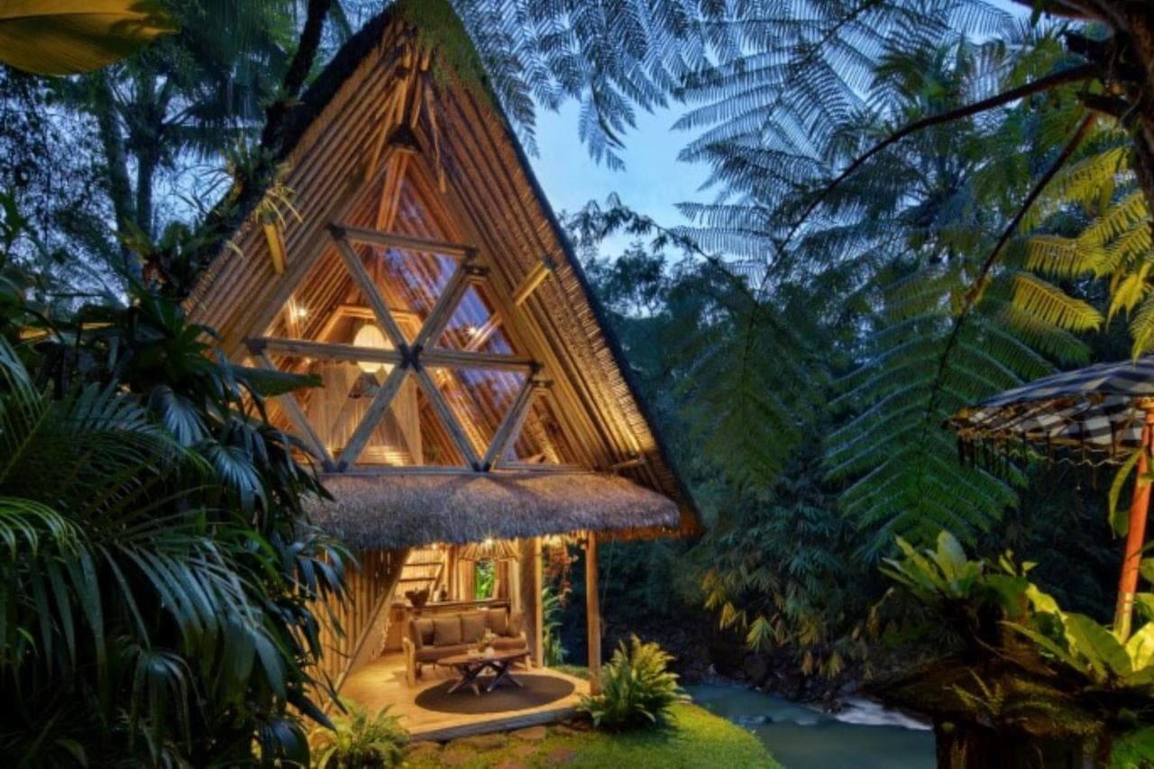 a cabin in the woods with a thatched roof at Hideout Eco Bamboo House Bali in Sidemen