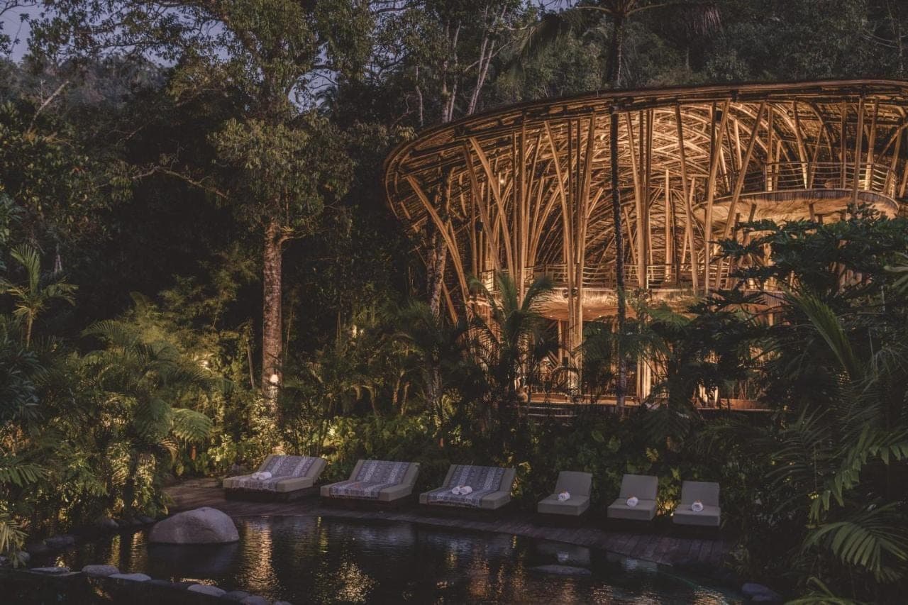 a group of lounge chairs in front of a bamboo structure at Hideout Eco Bamboo House Bali in Sidemen