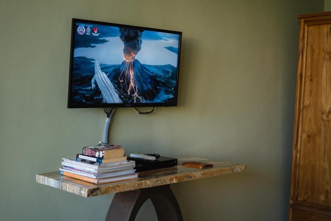 a tv on a wall with a shelf with books at Room Sweet Room - Seminyak Center, walk to the Beach in Seminyak