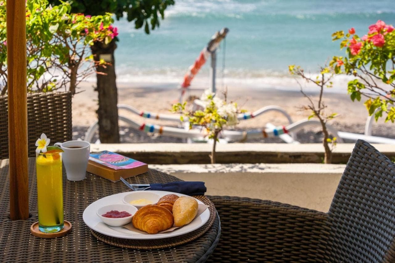 a table with a plate of pastries on the beach at Ibus Beach Hotel in Amed
