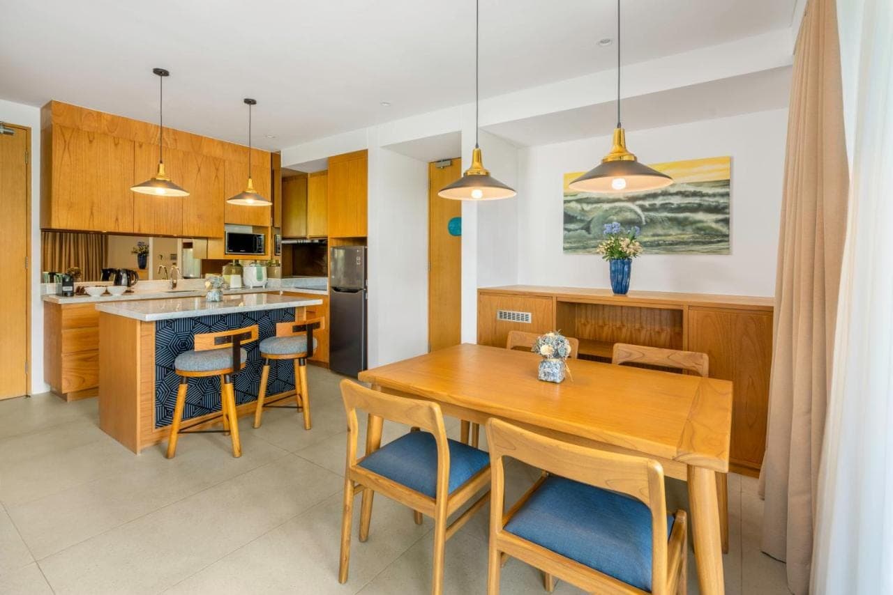 a kitchen and dining room with a wooden table and chairs at Citadines Berawa Beach Bali Resort in Canggu
